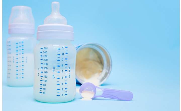 Bottle of milk or infant formula for a newborn on a blue background. The concept of motherhood and child care. View from above.